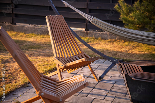 Foto Modern backyard patio with a metal fire pit, wooden lounge chairs, and a hammock