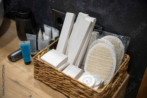 Cuadro en lienzo Luxury hotel bathroom amenities set in a woven basket on a wooden countertop
