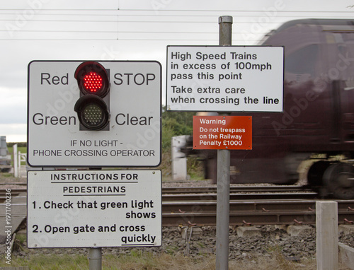 Bild auf Leinwand Warning signs where a footpath crosses a railway line, showing a red light indic