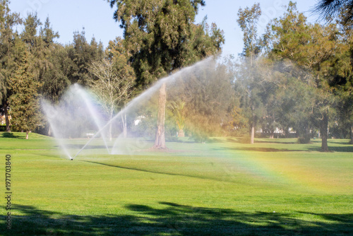 Photos Watering the fairway on golf course with large sprays of water creating a rainbo