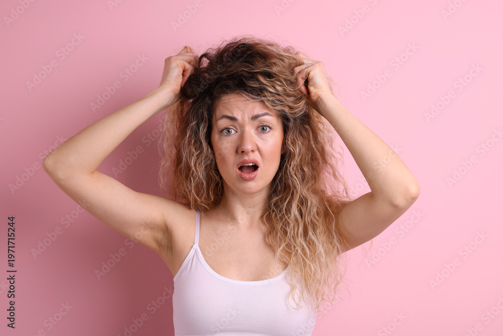 Fototapeta premium Unhappy woman with tangled hair on pink background