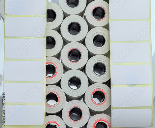 A high-angle composition of industrial adhesive label rolls and rectangular blank sticker strips, ideal for logistics, packaging, and office supply concepts.