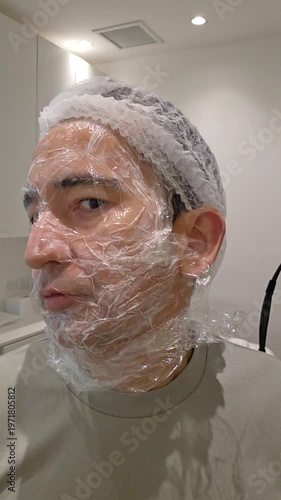 Treatment, cure of face skin in dermatology clinic. Scars procedure with problem skin for man. Man with cream with anesthesia and plastic film on his face before laser therapy procedure.