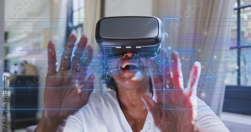 Fotografía Reaching senior woman wearing white top touching holographic interface in living