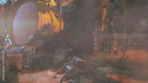 Showing bass drum with white drumhead and golden shell, pedalboard glowing at small stage corner
