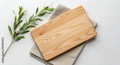 Wooden cutting board and olive branch on a neutral linen background