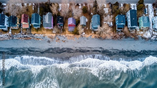 Overhead view captures colorful coastal dwellings bordering dynamic ocean waves during colder weather