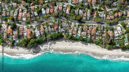Aerial view captures expensive oceanfront residences bordering a sandy shoreline and turquoise water
