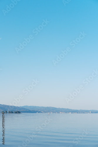 静寂な湖面に映る山並みと穏やかな水面、遠くの街並み