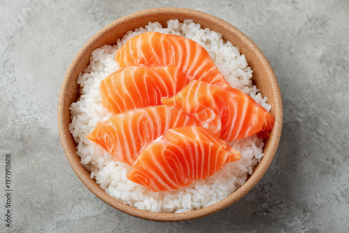 Top view of salmon sashimi slices served over rice in bowl with clean minimal background creating fresh Japanese cuisine concept
