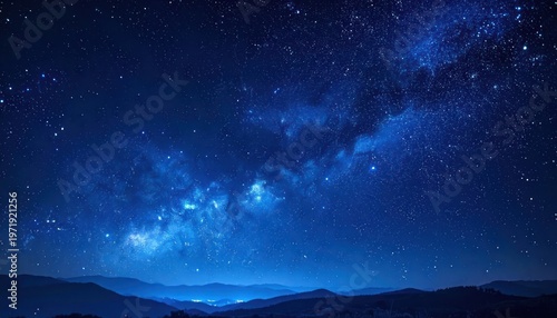 A breathtaking view of the Milky Way galaxy stretching across a vibrant, dark blue night sky above rolling hills.