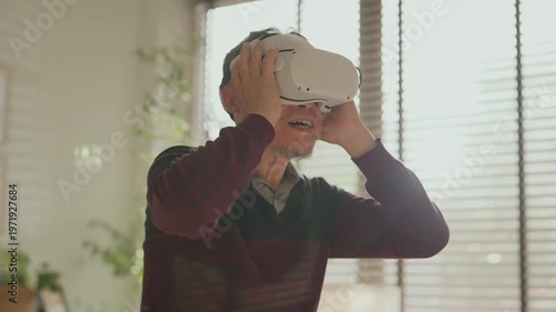 Senior Asian couple enjoying VR game experience in living room, elderly man and woman smiling while using virtual reality headset, fun technology activity, active lifestyle, modern entertainment at ho