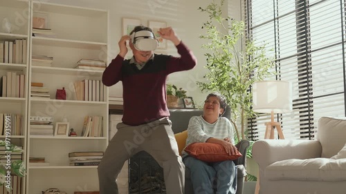 Senior Asian couple enjoying VR game experience in living room, elderly man and woman smiling while using virtual reality headset, fun technology activity, active lifestyle, modern entertainment at ho