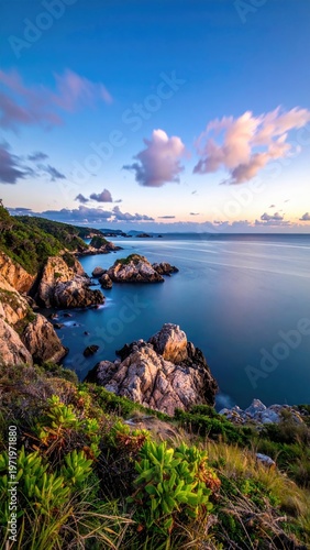 Coastal cliffs meet the sea at dusk, with colorful clouds above