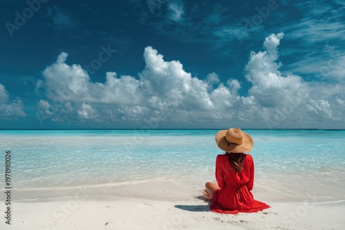 Serene woman in red dress and hat gazes at tranquil turquoise ocean under sky