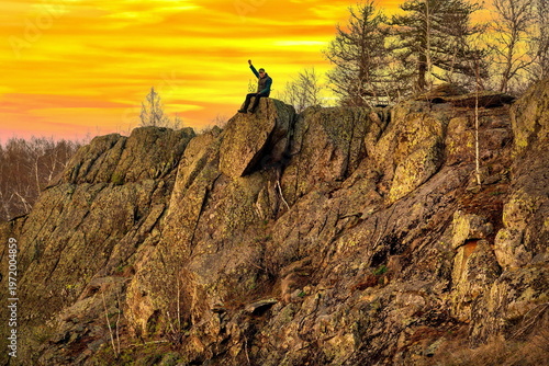 an elderly happy tourist stands on a high rock against the backdrop of the Ural mountains on a summer day