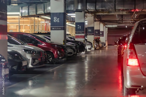 A row of cars in the basement parking lot of a shopping mall and a queue of cars about to exit
