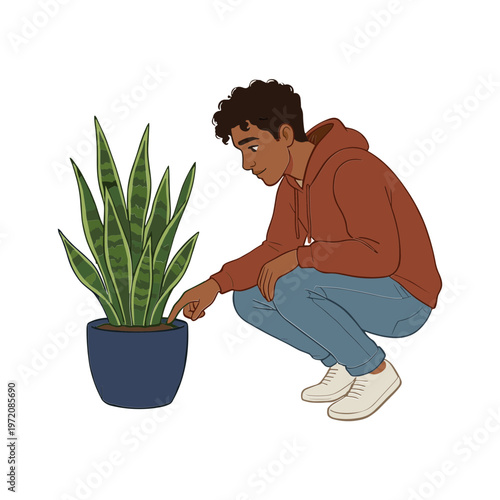 A man crouches beside a potted plant examining it closely indoors.
