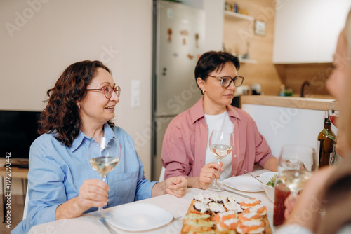 Fotografía Two women enjoy a lively dinner in a cozy dining space