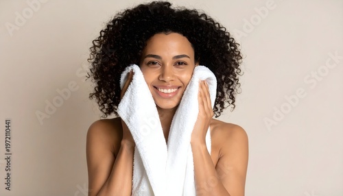 Smiling woman drying face with towel after skincare routine, fresh clean skin concept