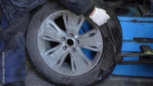 Mechanic removes car tire using a tire changing machine in auto repair shop. Close up process of wheel maintenance and service equipment in garage.