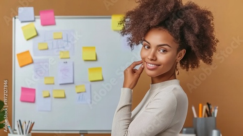 Woman with curly hair standing in front of digital whiteboard displaying charts and sticky notes, engaged in business planning or brainstorming.