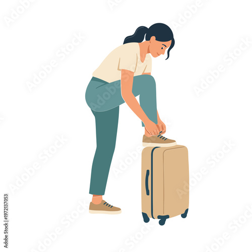 A woman is tying her shoe while kneeling on a travel suitcase in a casual setting.