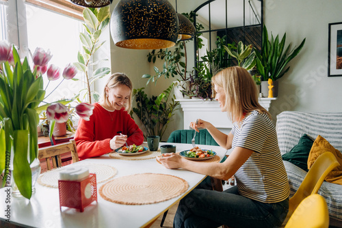 Fotografi Two friends share a delightful meal at a bright, plant-filled table