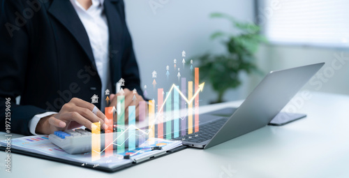 Business professional using calculator with laptop showing real estate growth chart hologram data analysis property investment performance increase strategy planning market trend forecast insight