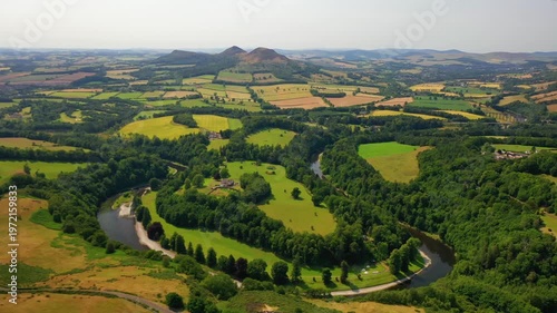 Panoramic aerial drone footage captures winding river through lush green countryside with rolling hills