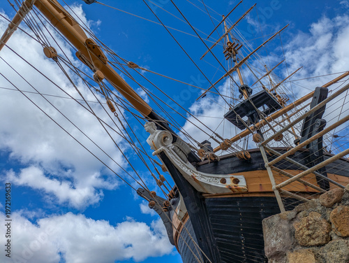 Fotografija Historic tall ship brig bow with figurehead masts and rigging against blue sky i