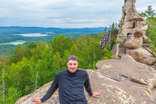 young handsome man on a rock on the Arakul shihan enjoys on a summer day