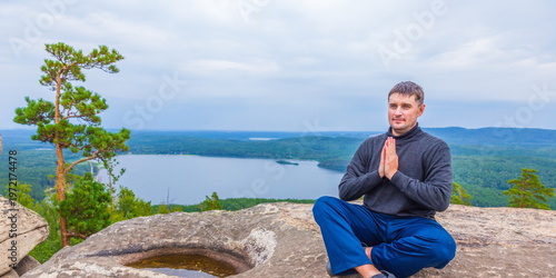 young handsome man on a rock on the Arakul shihan enjoys on a summer day