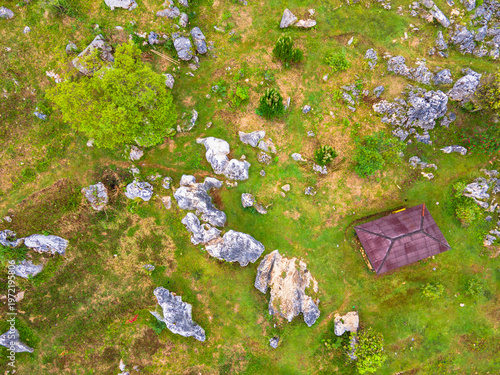 Top-down view of ancient rock formations scattered across green fields. Unique geological karst landscape with weathered limestone boulders, at Stone Garden, Padalarang, Bandung, Indonesia.