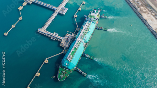 Massive LNG tanker ship assisted by tugboats docking at maritime terminal. Global energy logistics, liquid cargo container supply chain, and natural gas freight transport concept.