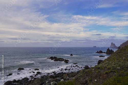View of the dramatic rocky coast of Anaga near Taganana and Benijos, Tenerife, with ocean waves and unique rock formations under a partly cloudy sky