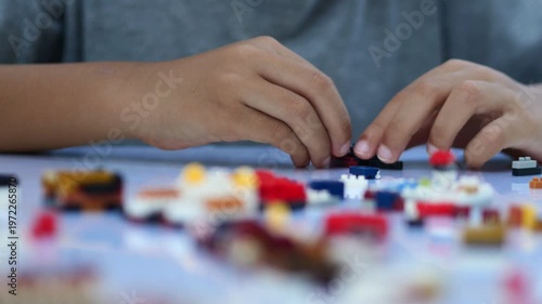 Child playing and building with colorful toy bricks, plastic blocks.	