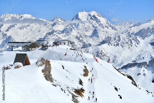 Bild auf Leinwand Slopes of Courchevel ski resort with skiers and snowy mountains in the backgroun