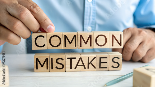 Fotografie Businessman arranging wooden blocks spelling out common mistakes concept for bus