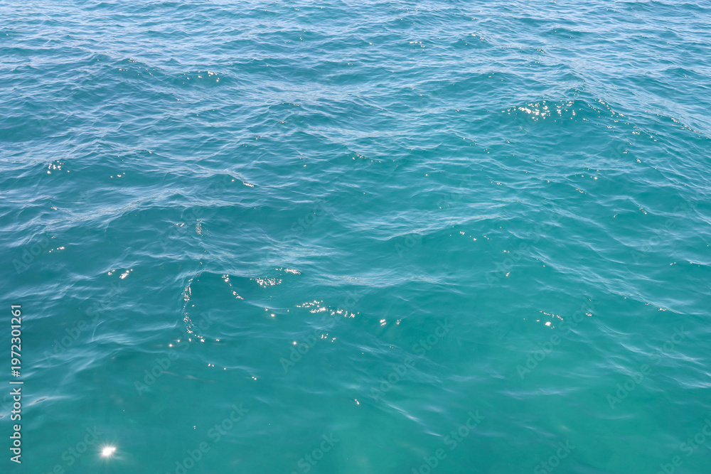 Fototapeta premium Turquoise seawater texture with ripples and sun glare. Beautiful blue ocean water background