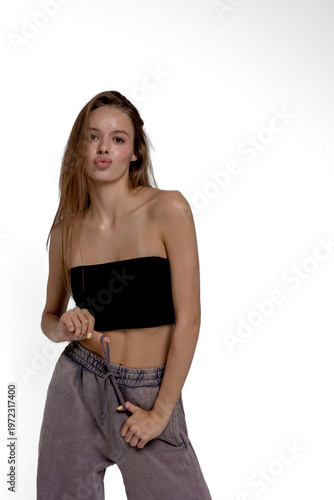 Young woman poses confidently in casual clothing with a playful expression on a neutral background