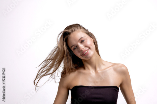 Young woman smiling with long hair against white background in a studio setting during a photoshoot session