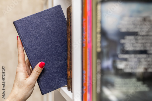Foto a woman's hand takes a blue book from the shelf