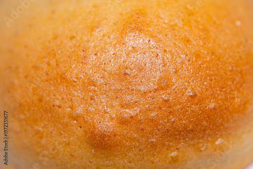 Full frame macro texture of a baked golden brown coffee pastry crust with tiny craters and glossy finish.