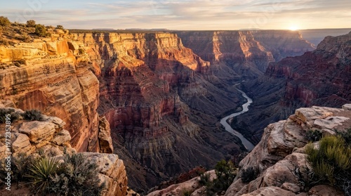 A massive desert canyon system photographed at first light, stratified sandstone walls glowing in bands of vermillion, ochre and cream as the sun strikes the upper rim, deep purple