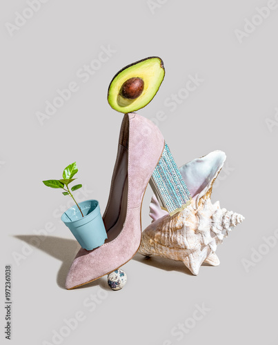 Stylish high heel shoe with avocado, plant, and seashell in a creative artistic arrangement