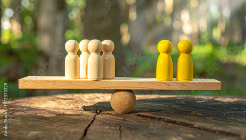 Wooden balance scale on tree stump in sunlit forest, five natural figurines balanced with two yellow ones—evoking equality, fairness, and harmony between groups in nature’s quiet equilibrium.