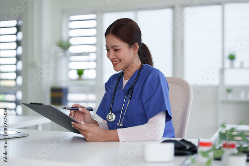 Asian adult medical professional nurse doctor reviews patient records clipboard writing notes healthcare office clinic environment smiling professional diligent