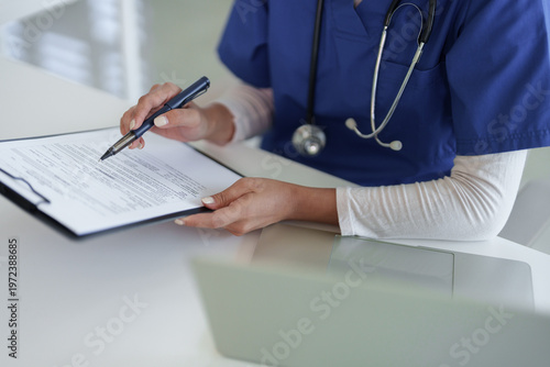 Foto Healthcare professional adult hands reviewing patient medical document with pen