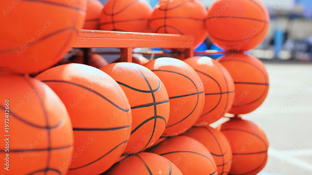 Obraz premium Many orange basketballs stacked on a storage rack, representing sports and team games